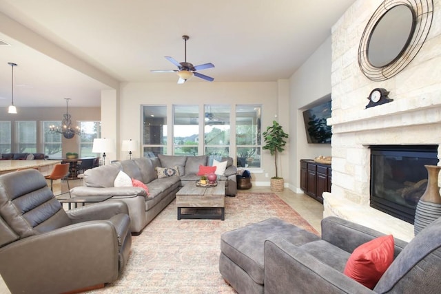 living room featuring ceiling fan with notable chandelier and a fireplace