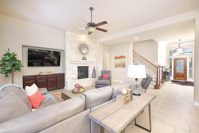 living room featuring ceiling fan, a fireplace, and light tile patterned floors