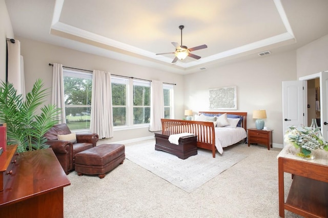 carpeted bedroom featuring a tray ceiling and ceiling fan