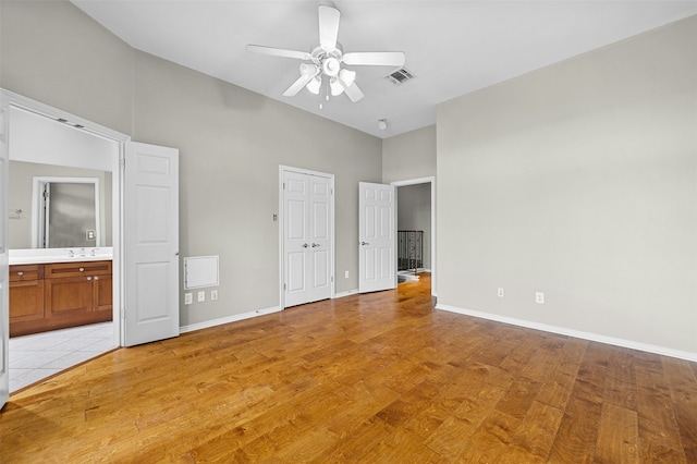 unfurnished bedroom featuring light wood-type flooring, ensuite bath, ceiling fan, and sink