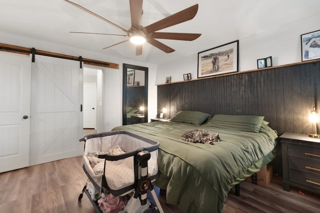 bedroom featuring a barn door, ceiling fan, and hardwood / wood-style floors