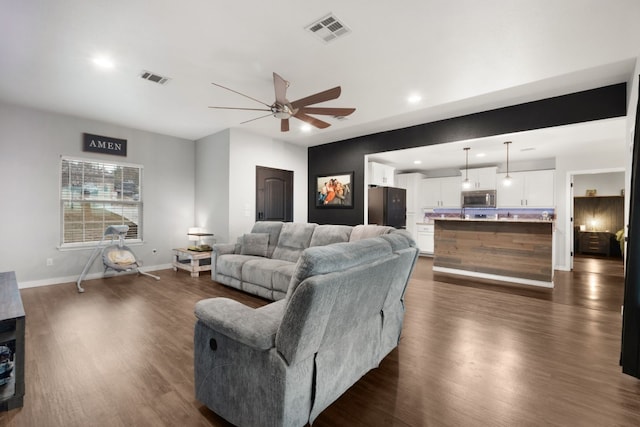 living room featuring ceiling fan and dark wood-type flooring