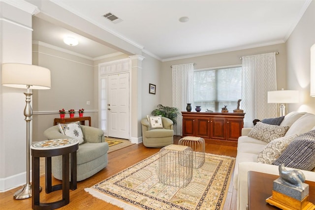 living room with light hardwood / wood-style floors, ornate columns, and crown molding