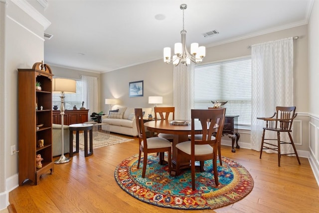 dining space with crown molding, light hardwood / wood-style floors, and a notable chandelier