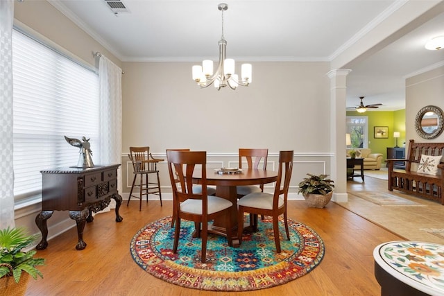 dining area with hardwood / wood-style floors, ceiling fan with notable chandelier, ornate columns, and ornamental molding