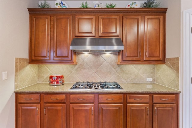 kitchen featuring stainless steel gas stovetop, light stone countertops, and decorative backsplash