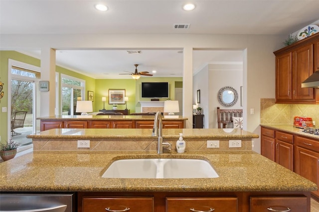 kitchen featuring a center island with sink, backsplash, ceiling fan, and sink