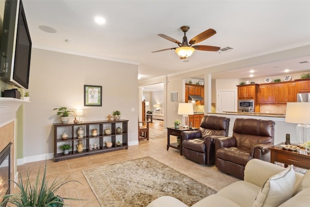 living room with ceiling fan, crown molding, and a tile fireplace