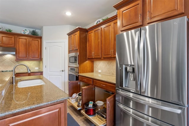 kitchen featuring decorative backsplash, sink, stone countertops, and appliances with stainless steel finishes