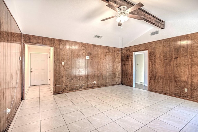 empty room with wood walls, ceiling fan, lofted ceiling with beams, and light tile patterned floors