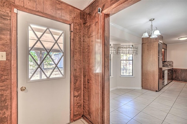 entryway with a chandelier, wooden walls, plenty of natural light, and crown molding