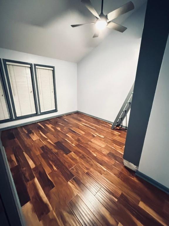 empty room with lofted ceiling, ceiling fan, and dark wood-type flooring