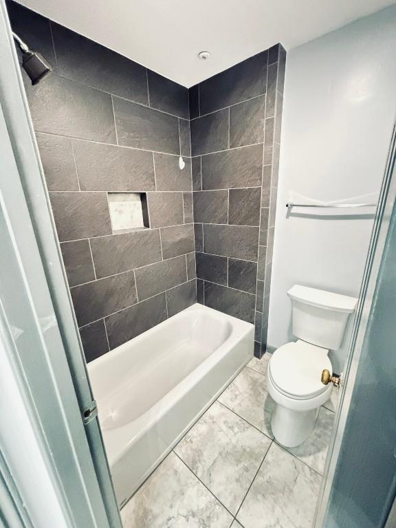 bathroom featuring tiled shower / bath and toilet