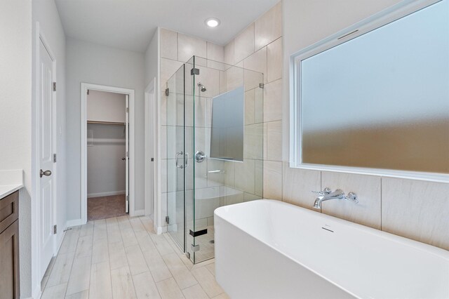 bathroom featuring shower with separate bathtub and vanity