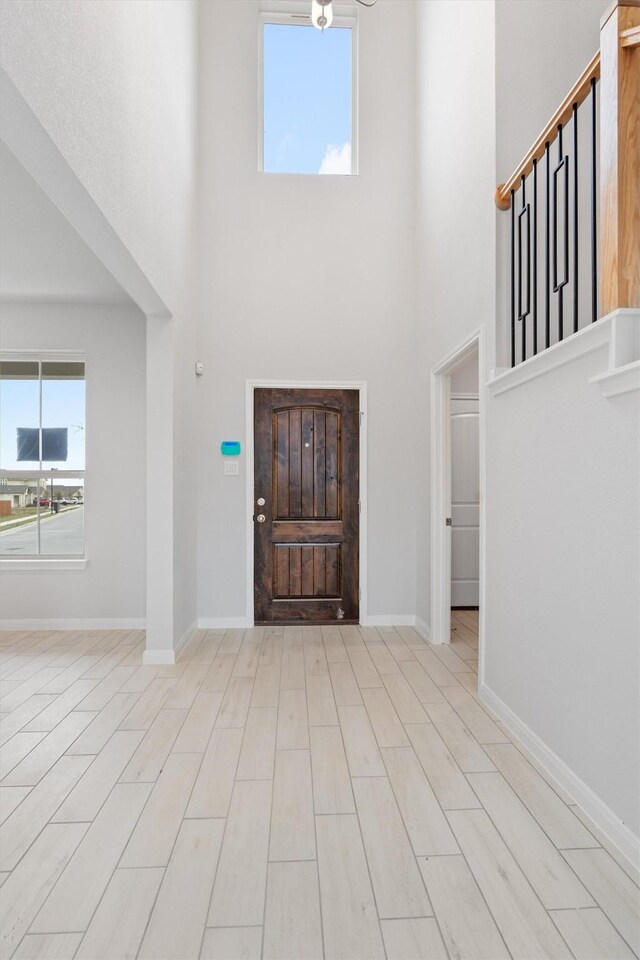 foyer featuring a towering ceiling and light wood-type flooring