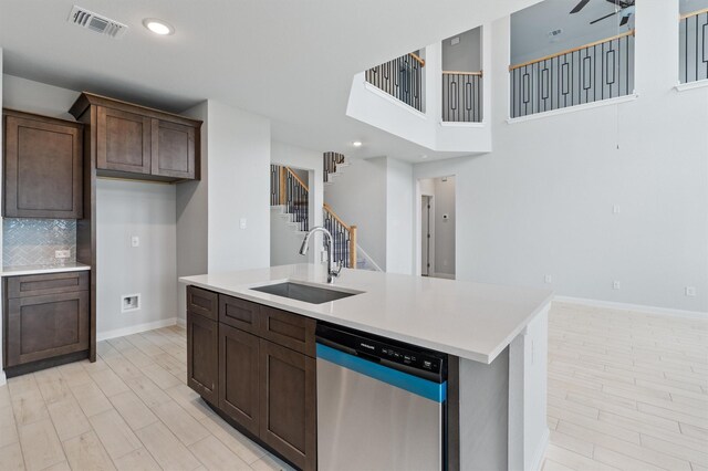 kitchen with backsplash, a center island with sink, sink, stainless steel dishwasher, and dark brown cabinets