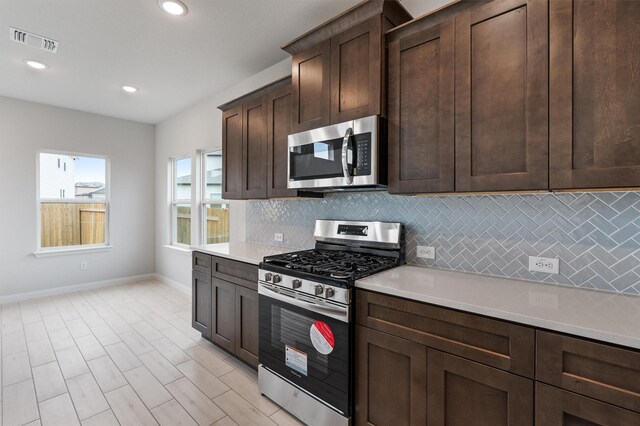 kitchen with dark brown cabinets, backsplash, and appliances with stainless steel finishes