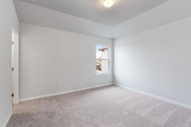 carpeted spare room with lofted ceiling