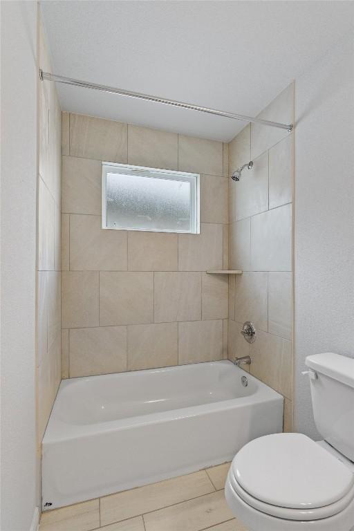 bathroom with tiled shower / bath combo and toilet