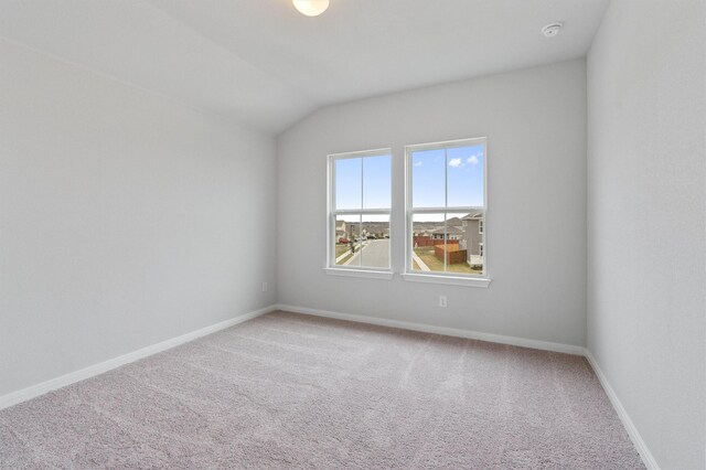 spare room with carpet floors and vaulted ceiling