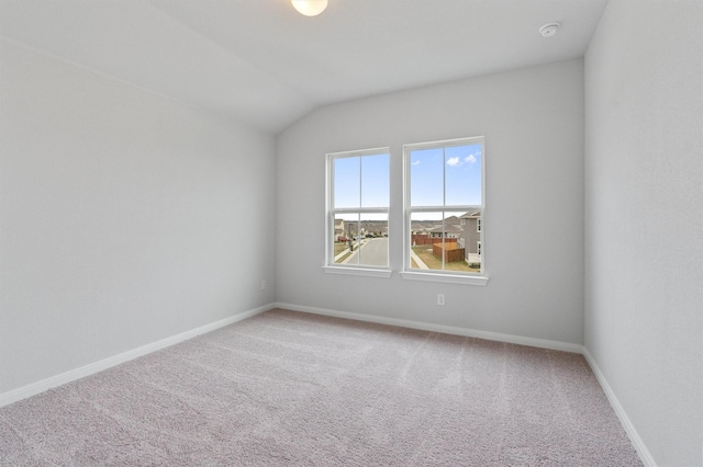 carpeted empty room featuring lofted ceiling