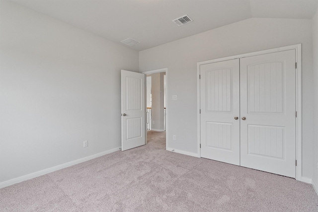 unfurnished bedroom featuring light colored carpet, lofted ceiling, and a closet