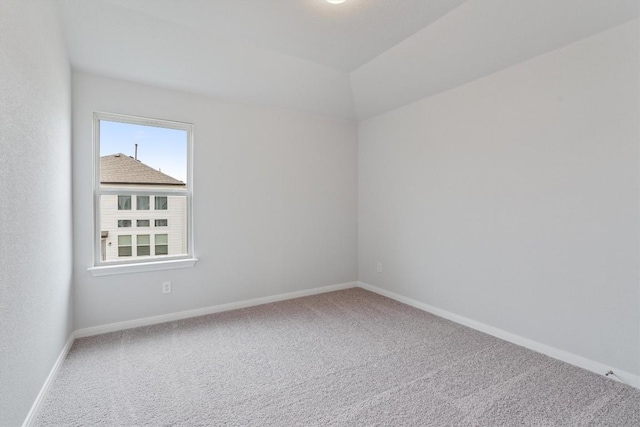 carpeted spare room with a wealth of natural light and lofted ceiling