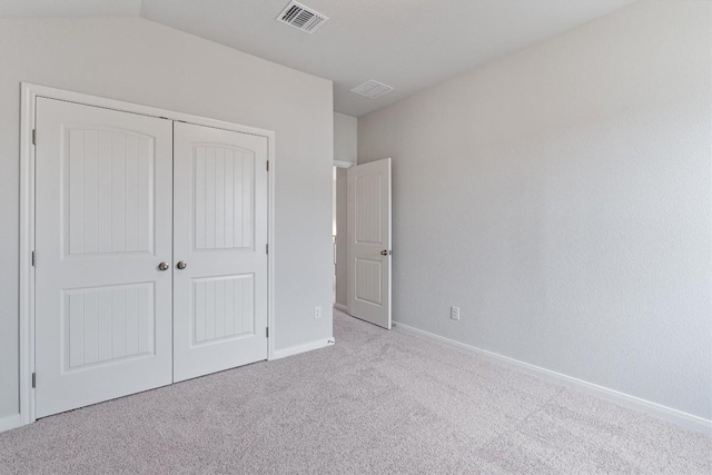 unfurnished bedroom with lofted ceiling, light carpet, and a closet