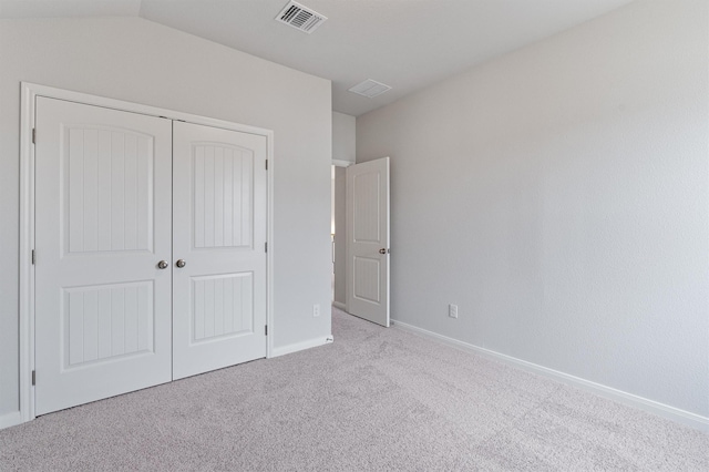 unfurnished bedroom with light carpet, vaulted ceiling, and a closet