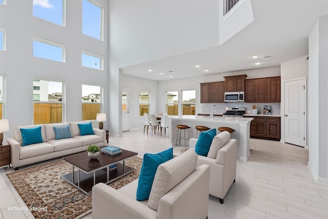 living room featuring a high ceiling, plenty of natural light, and sink