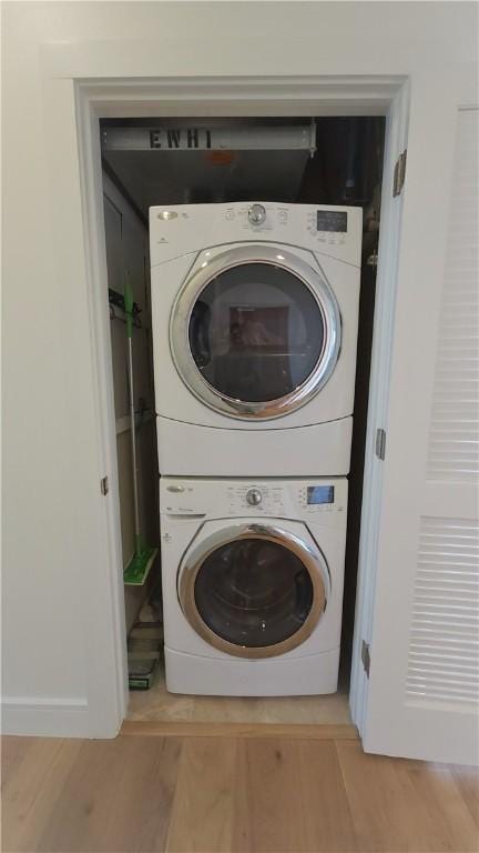 clothes washing area featuring light wood-type flooring and stacked washer / dryer