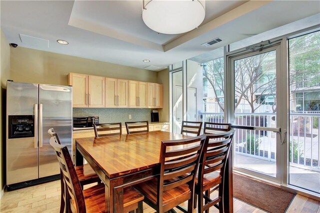 dining room with a tray ceiling, a healthy amount of sunlight, and light wood-type flooring