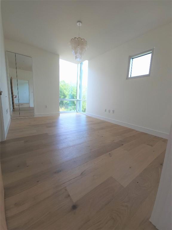 unfurnished room with light wood-type flooring and an inviting chandelier