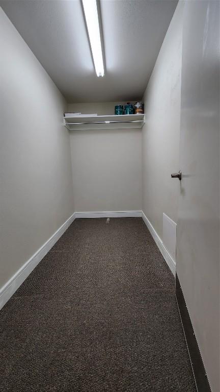 walk in closet featuring dark carpet