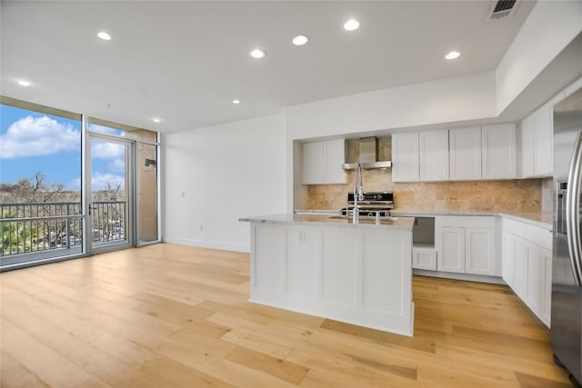 kitchen featuring light wood-style floors, tasteful backsplash, visible vents, and a wall of windows