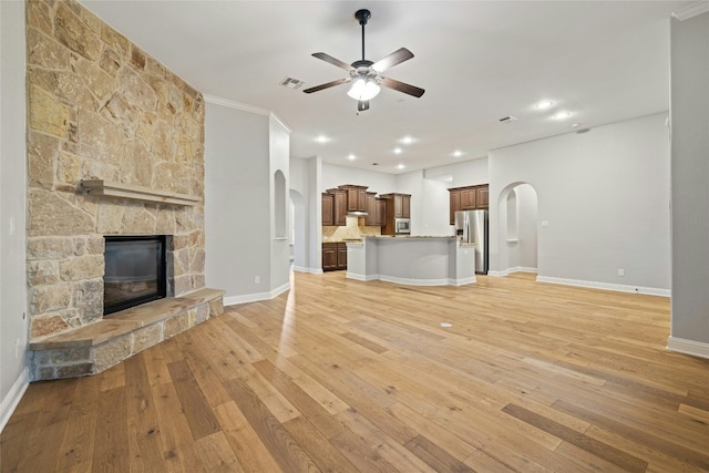 unfurnished living room featuring ceiling fan, a fireplace, and light hardwood / wood-style flooring