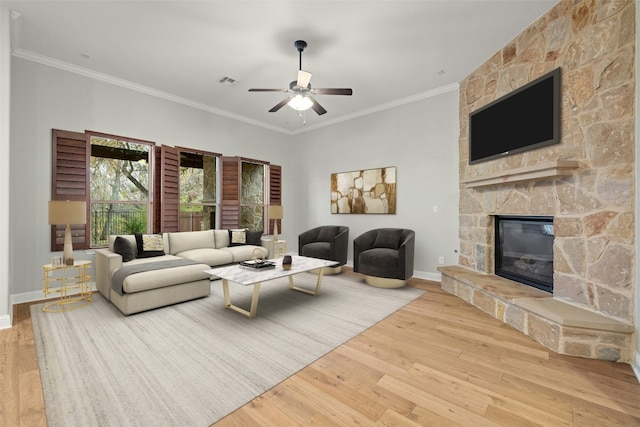 living room featuring crown molding, a fireplace, ceiling fan, and light wood-type flooring