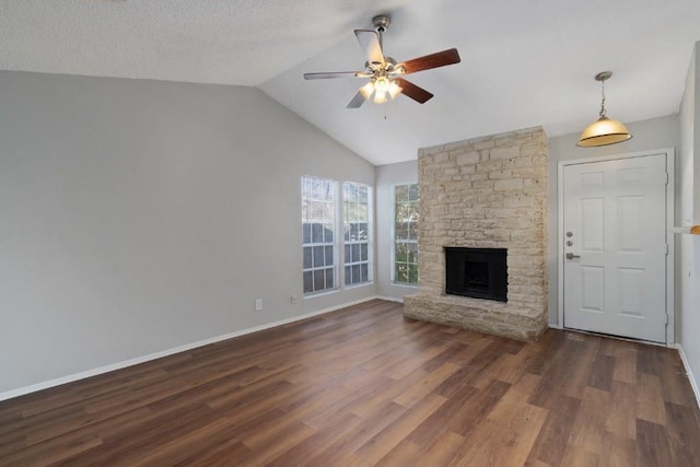 unfurnished living room featuring a textured ceiling, vaulted ceiling, ceiling fan, dark hardwood / wood-style floors, and a stone fireplace