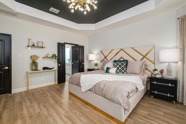 bedroom featuring light hardwood / wood-style floors, connected bathroom, and a tray ceiling