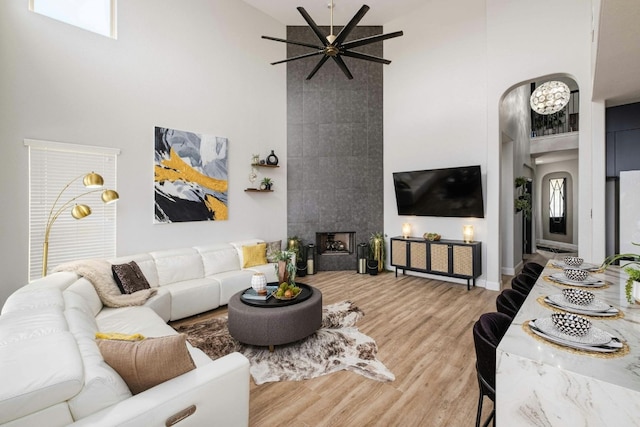 living room featuring a tiled fireplace, ceiling fan, hardwood / wood-style floors, and high vaulted ceiling