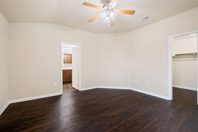 unfurnished bedroom with a spacious closet, dark wood-type flooring, a closet, ceiling fan, and ensuite bathroom