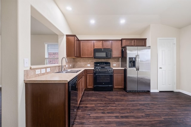 kitchen featuring tasteful backsplash, dark wood-type flooring, vaulted ceiling, black appliances, and sink