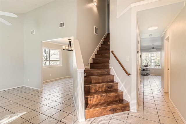 stairs featuring tile patterned floors, crown molding, and an inviting chandelier