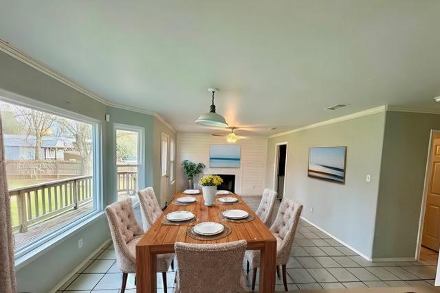 282 Spring River Dr, Martindale, TX 78655 - dining space with plenty of natural light, light tile patterned flooring, a ceiling fan, a fireplace, and crown molding