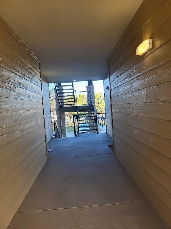 hallway with concrete flooring and wood walls