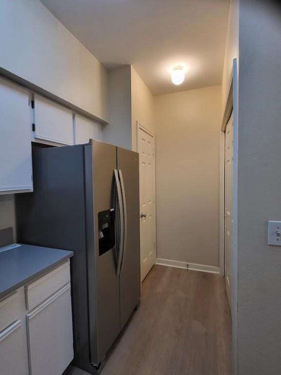 kitchen featuring white cabinets, stainless steel refrigerator with ice dispenser, and light wood-type flooring