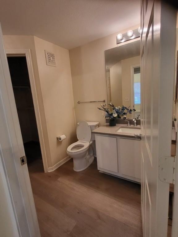 bathroom with toilet, vanity, and hardwood / wood-style flooring