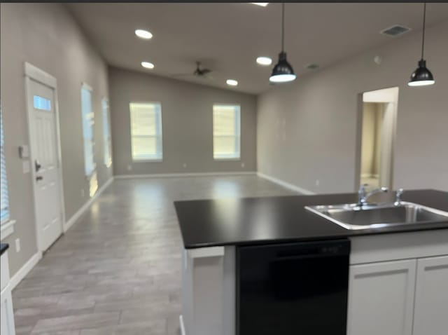 kitchen featuring pendant lighting, dishwasher, white cabinets, sink, and vaulted ceiling