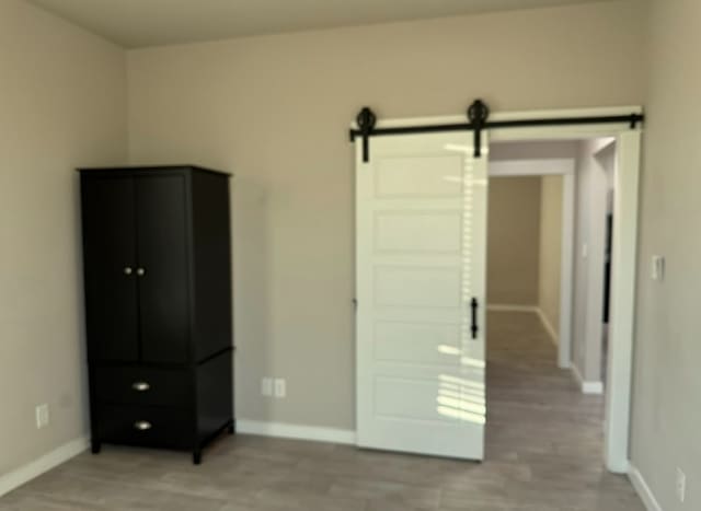 427 Pintail Loop, San Marcos, TX 78666 - unfurnished bedroom featuring a barn door and light wood-type flooring