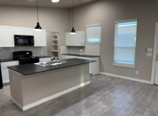 kitchen with white cabinetry, a center island with sink, black appliances, and decorative light fixtures